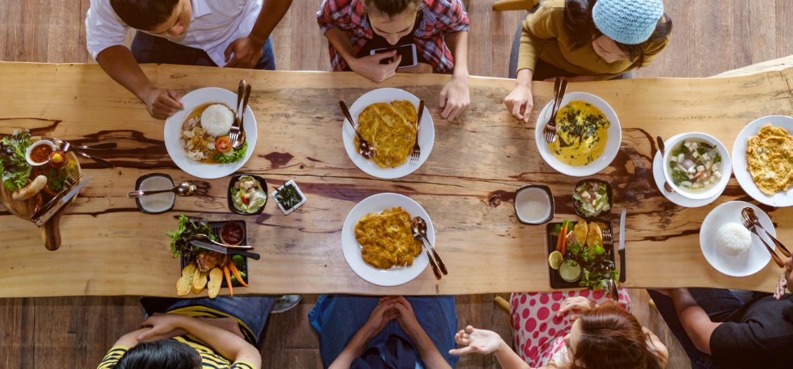 Menschen sitzen am Tisch voller Essen